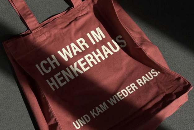 Ein rostroter Shopper mit der Aufschrift "Ich war im Henkerhaus und kam wieder raus."